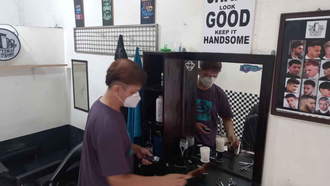 Ageng Patmoko providing barber services